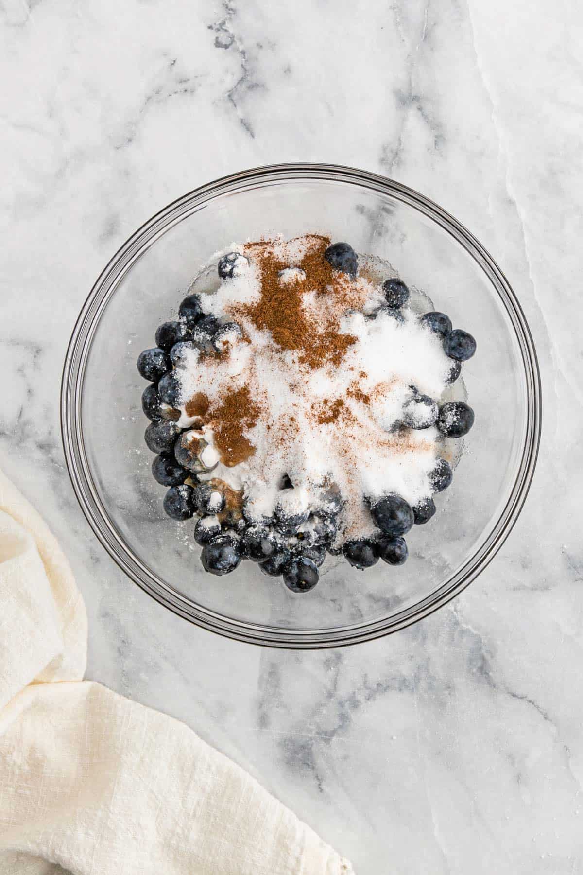 Blueberries in a bowl topped with sugar and spices.