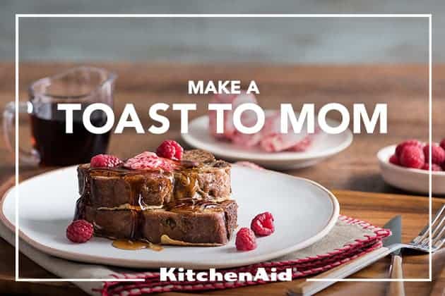 Toast to Mom Banana Bread French Toast served on a white plate with a cup of coffee and fresh raspberries in the background
