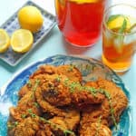delicious fried chicken on a blue plate with sweet tea pitcher and lemon slices nearby