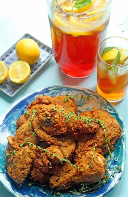 delicious fried chicken on a blue plate with sweet tea pitcher and lemon slices nearby