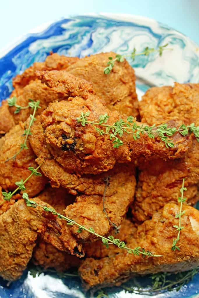 Close up of a pile of sweet tea fried chicken sitting on a blue and white plate