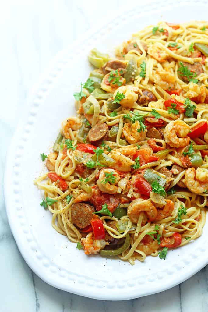Cajun Shrimp Pasta with shrimp, sausage and cajun spices served on a white, round tray
