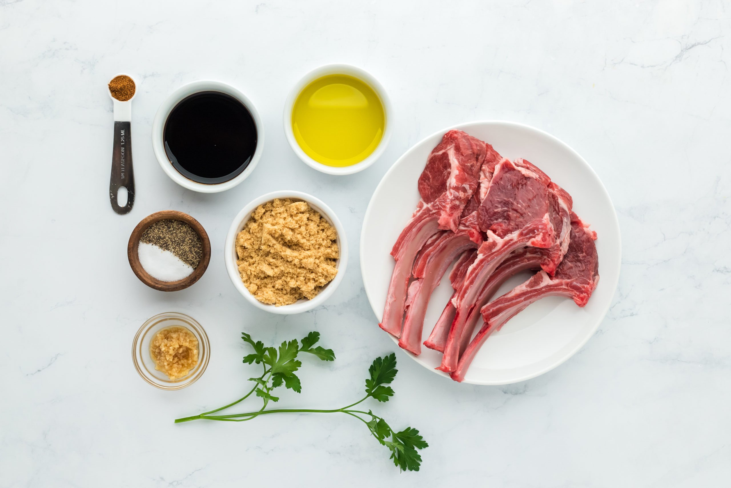 Lamb chops, oil, balsamic vinegar, brown sugar, seasoning on white countertop