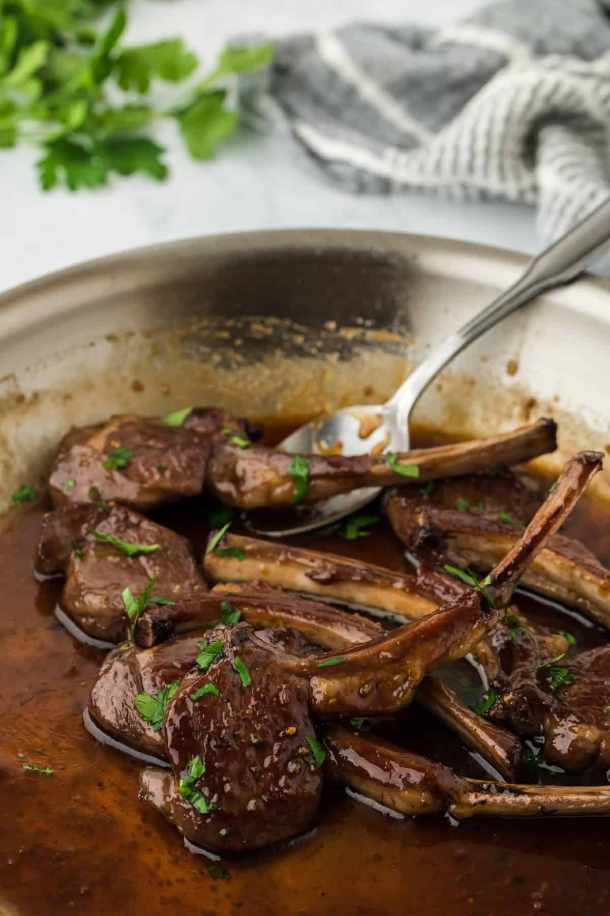 Lamb loin chops basting in a sauce in a skillet