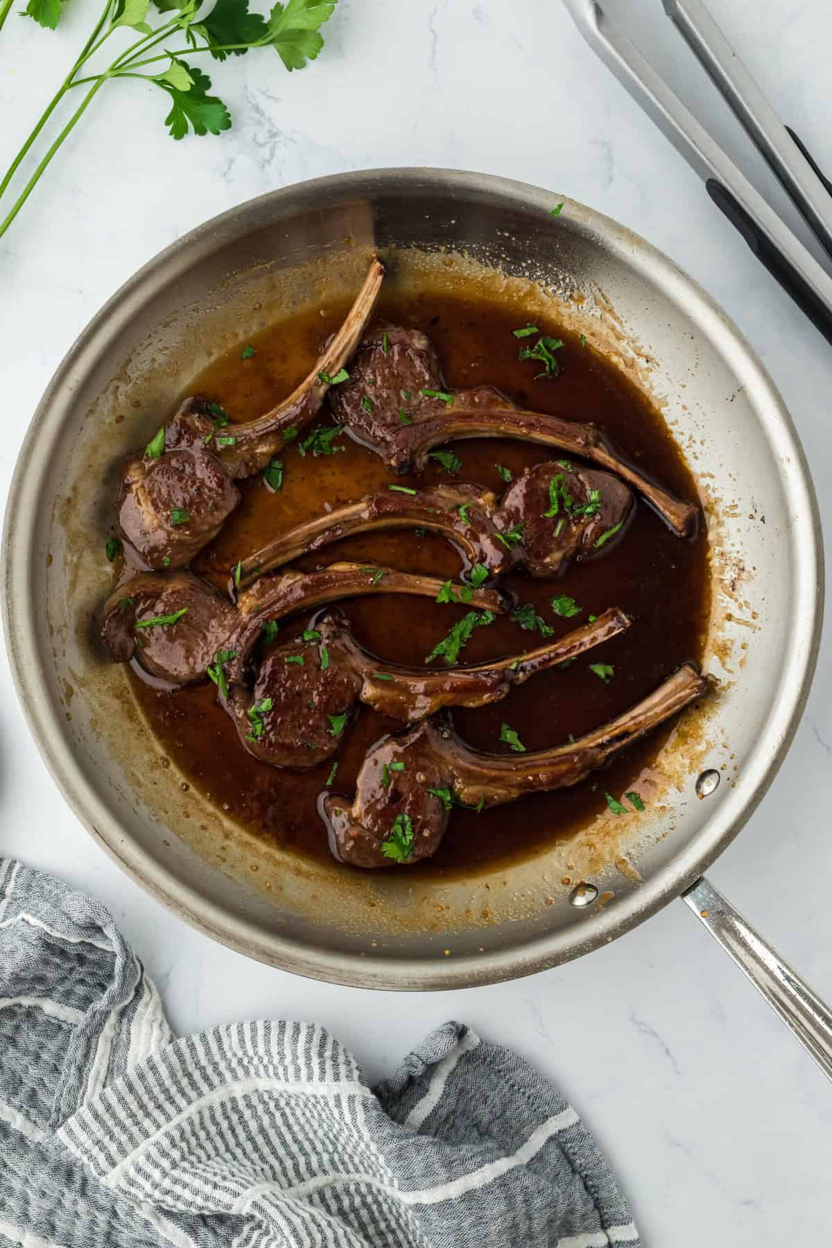 Lamb loin chops with parsley basting in a sauce in a skillet