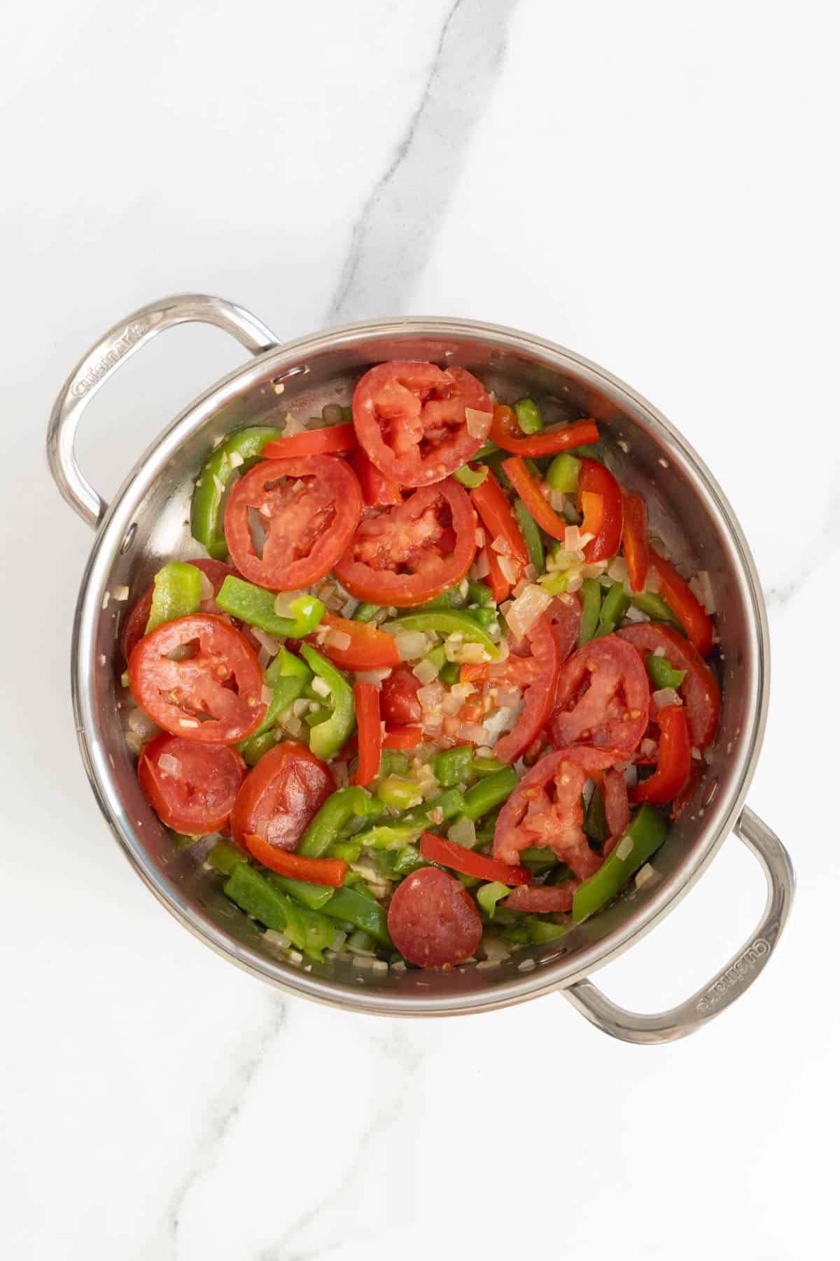 Sautéed green and red bell peppers with tomato slices added to the pot
