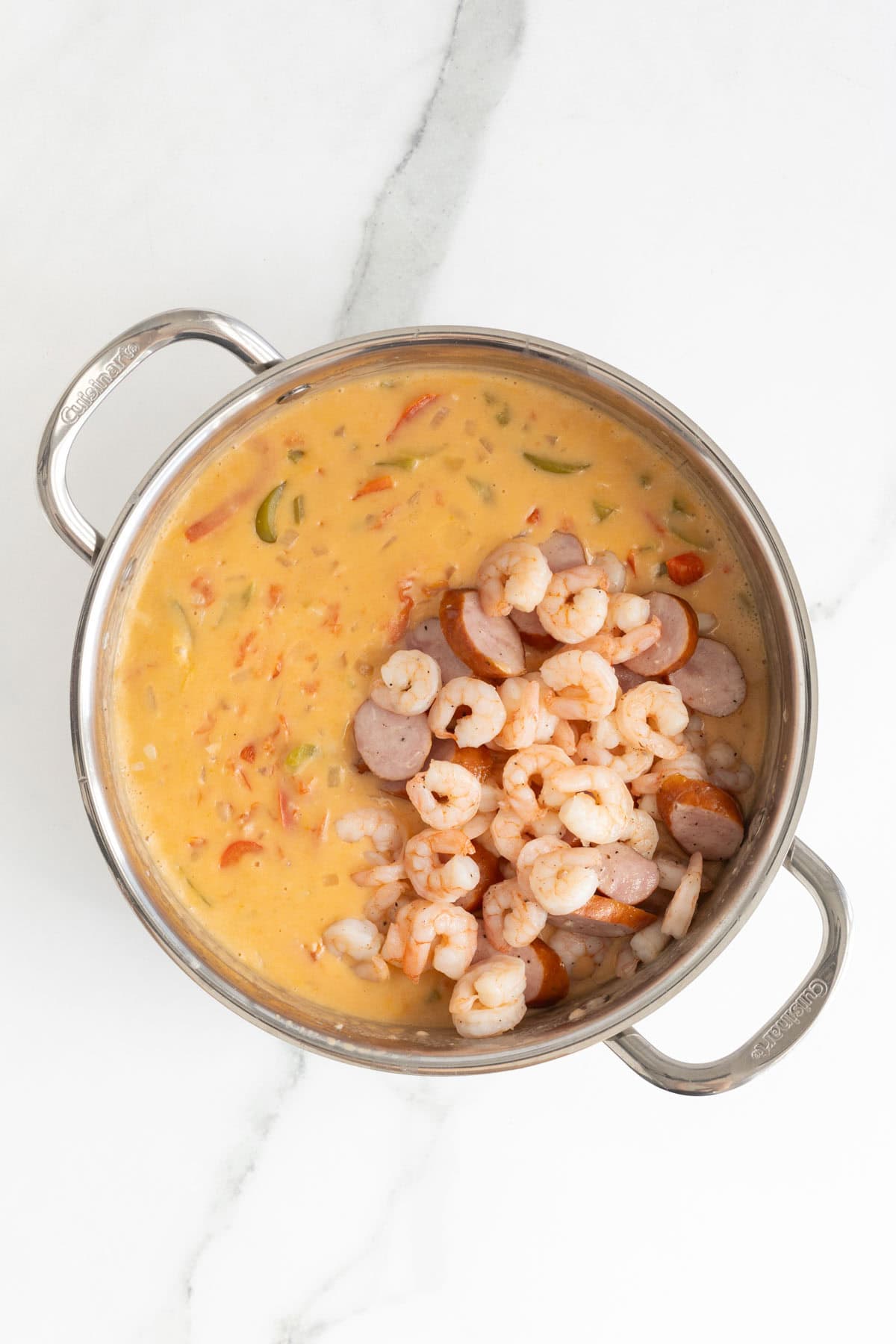 Cooked shrimp and sausage added to the creamy sauce in the pot