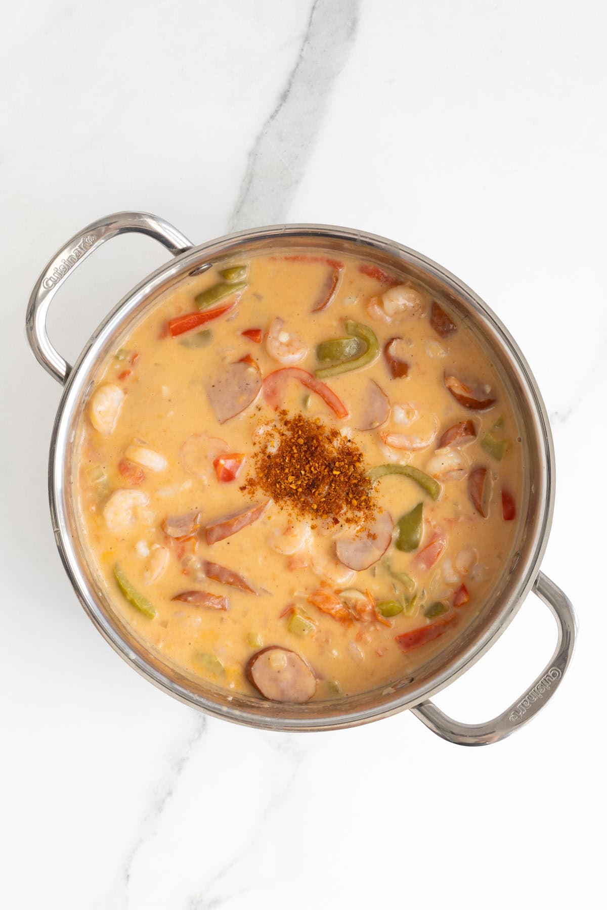 Cajun seasoning sprinkled on top of creamy shrimp, sausage, and pepper mixture