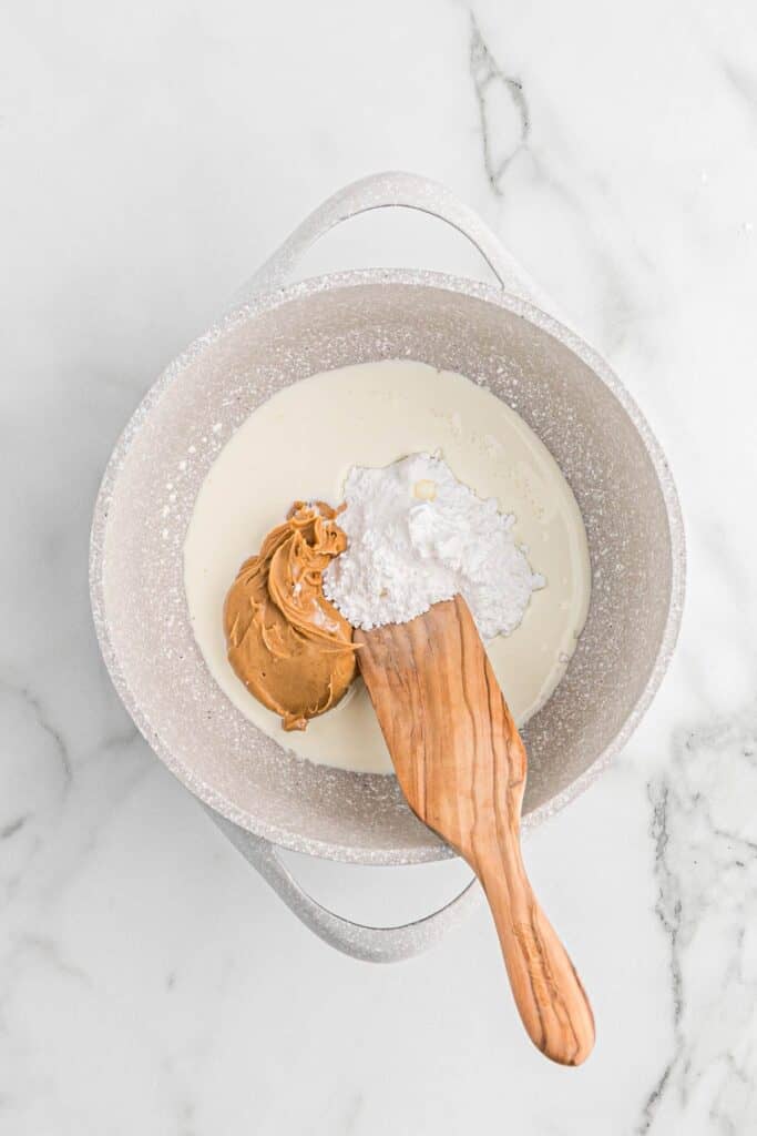Whipping cream, peanut butter, and powdered sugar in a pot to heat.