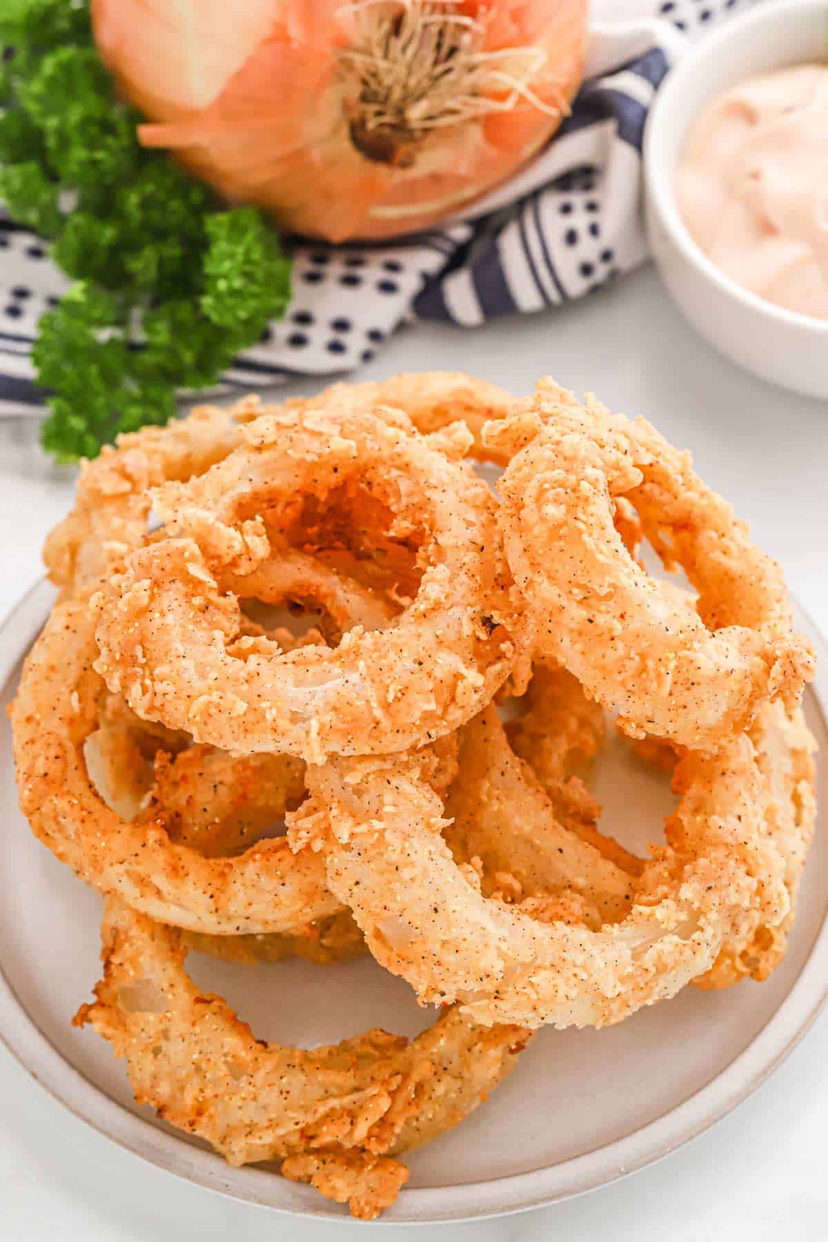 A plate of the best onion rings on the table with sauce.