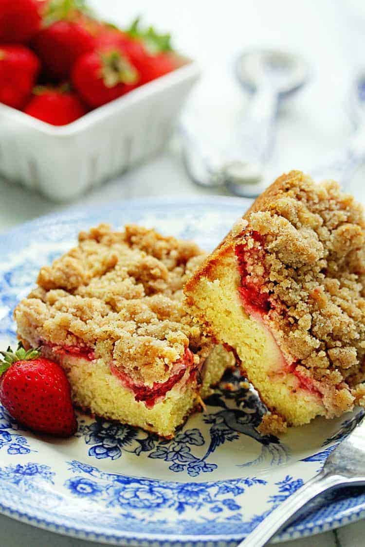 A close up of strawberry crumb cake slices on a blue and white plate