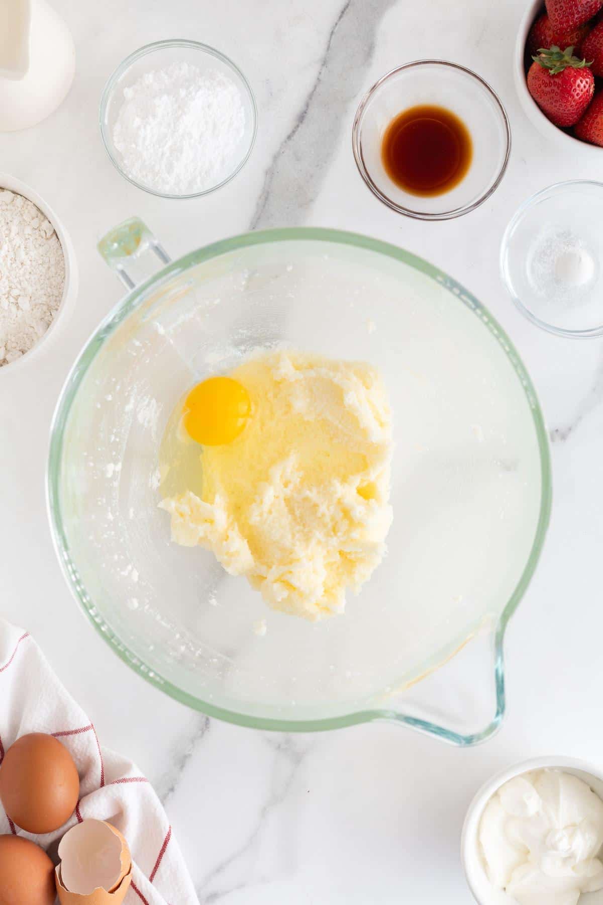 A whole egg added to the creamed mixture in the glass bowl, mid-preparation