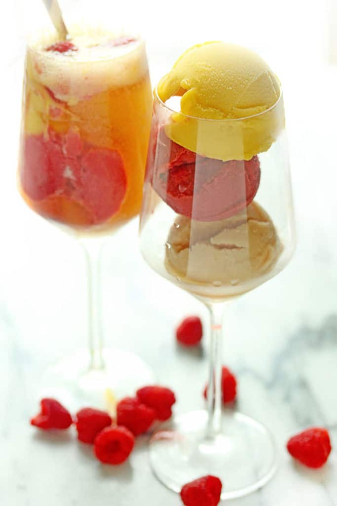 Summer Sorbet Float served in a wine glass surrounded by fresh raspberries