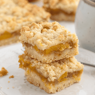 Peach Crumble Bars stacked on top of each other on a white plate