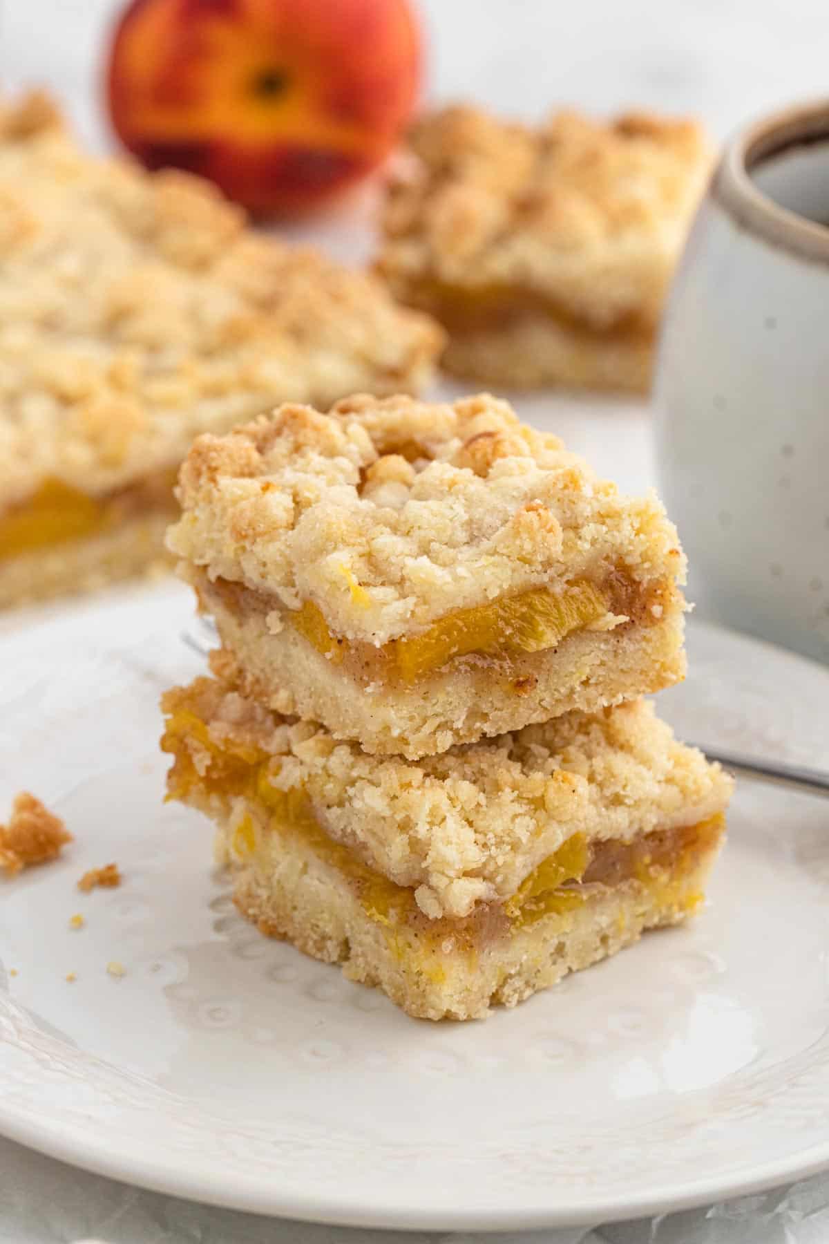 Peach Crumble Bars stacked on top of each other on a white plate