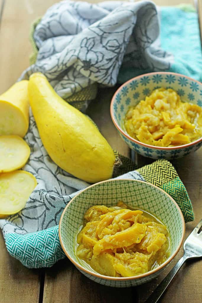 Two colorful bowls of sauteed yellow squash with a sliced and whole yellow squash next to the bowls