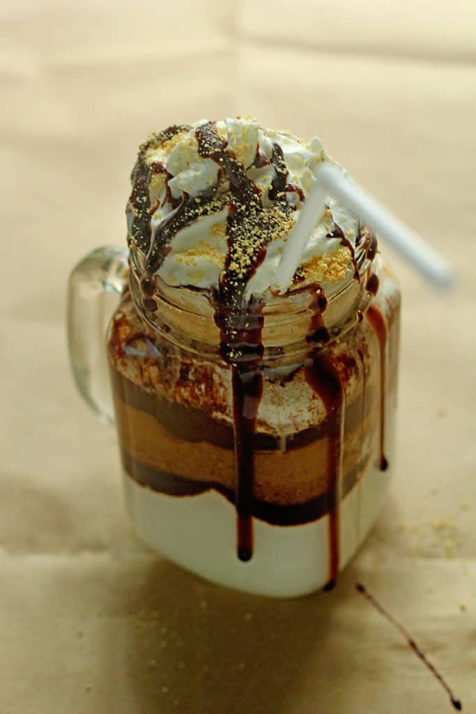Close up of a S'mores Iced Coffee contained in a glass mug with a white straw