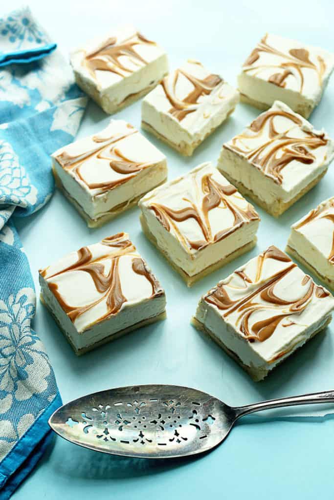 Several cookie cheesecake swirl bars on a light blue background