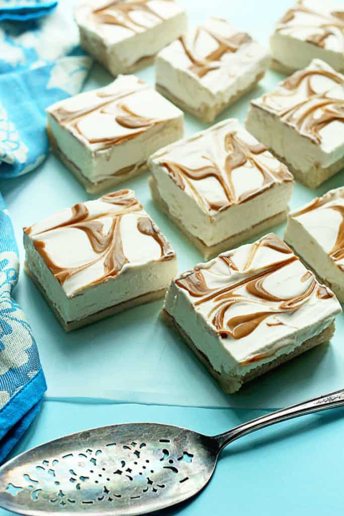 Close up of several cookie cheesecake swirl bars on a light blue background