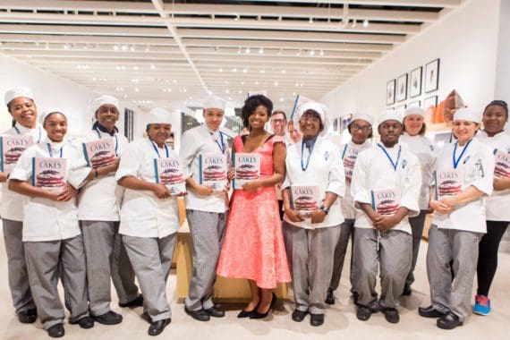 Jocelyn Delk Adams posing with cooking students and her cookbook