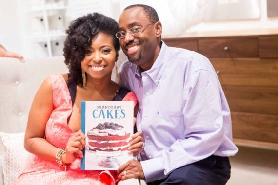 Jocelyn Delk Adams posing for a photo with her husband and a copy of her cookbook