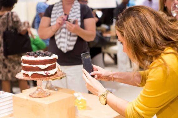 Attendee taking a photo of the red velvet cake with blueberry butter cream on her cell phone