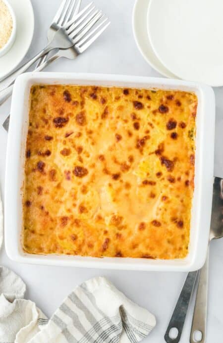 Overhead view of a golden-brown baked potato and squash gratin in a white baking dish