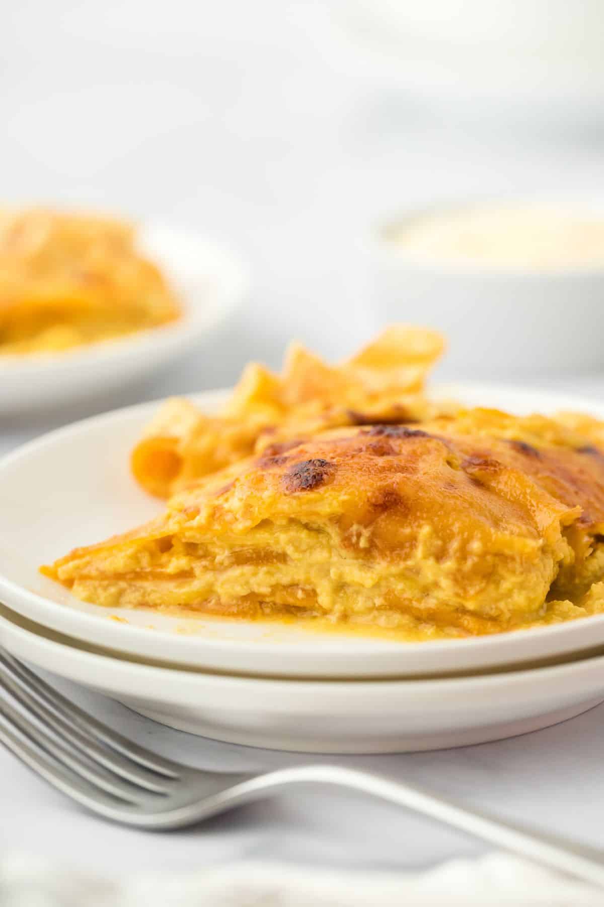 A slice of potato and squash gratin on a white plate, showing its creamy layers