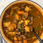 A simple beef stew recipe in a pot with a large spoon stirring on a white background with parsley in the background