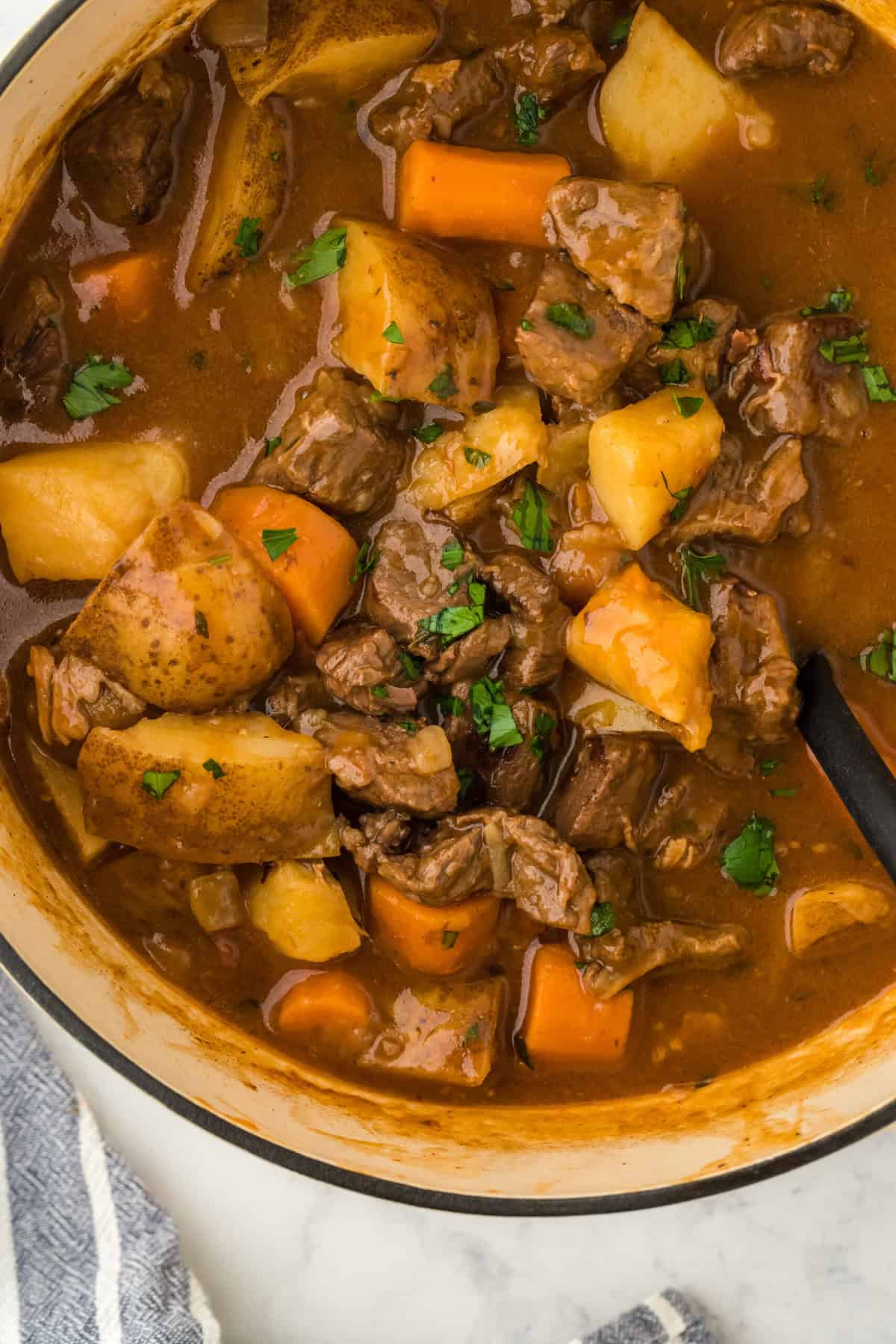 A close up of an easy beef stew recipe in a large pot on a white background