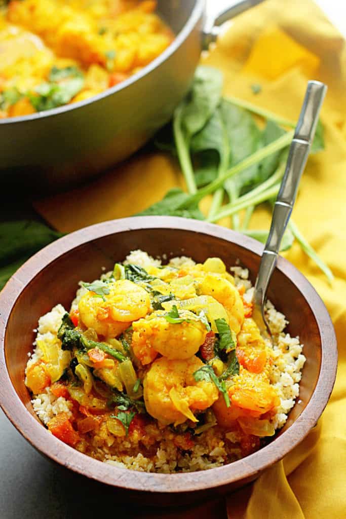 Close up of Light Curry Shrimp served in a wooden bowl with a fork in it and the entire dish next to it