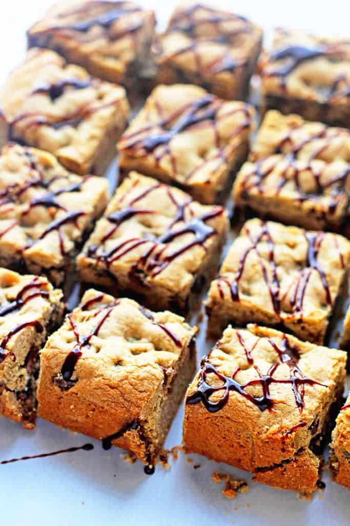 Several chocolate chip cookie bars topped with a drizzle of chocolate sauce
