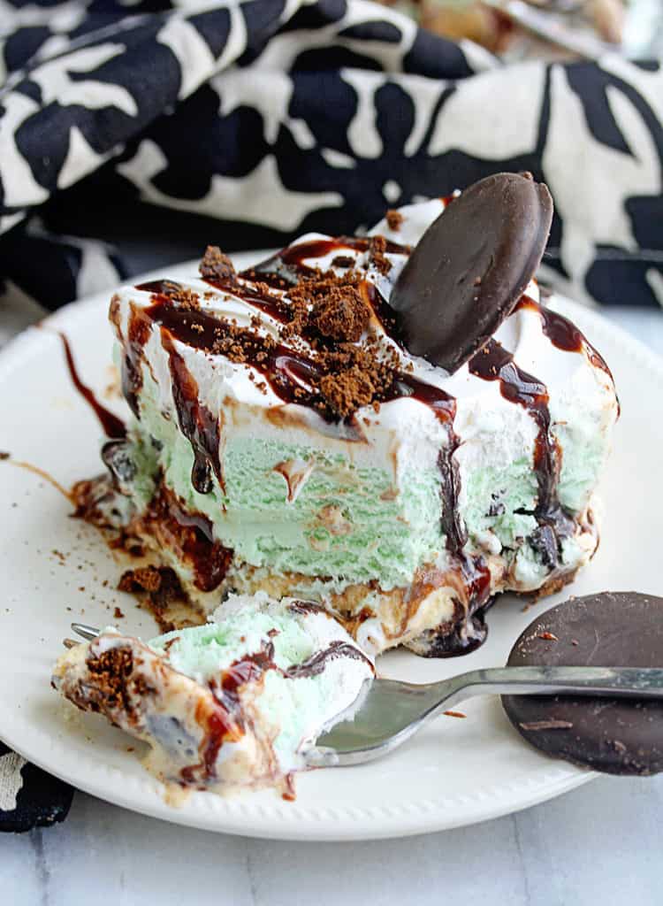 Close up of a piece of Girl Scout Cookie Mint Chocolate Ice Cream Cake sitting on a white plate with a fork