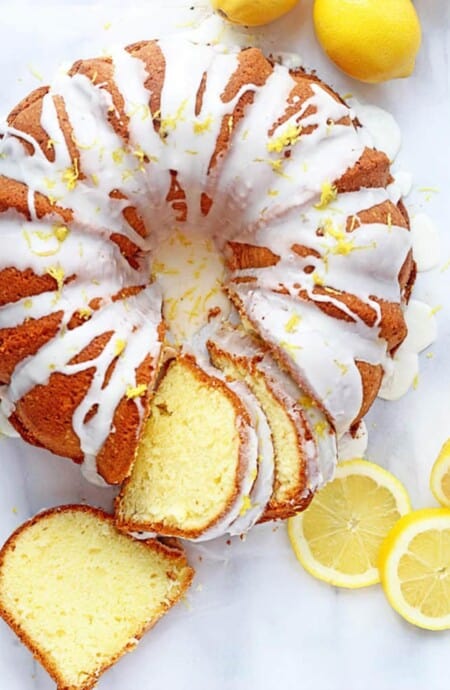 Lemon cake baked in bundt pan on the table slice slices cut and fresh lemons.