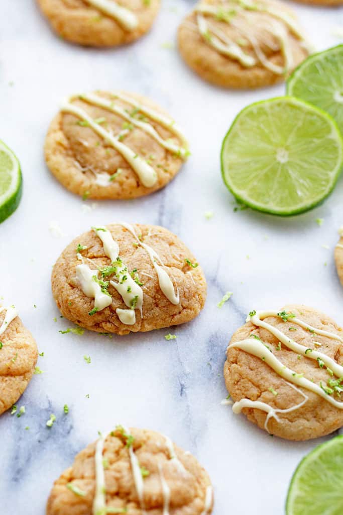 Close up of several key lime pie cookies on a marble surface with key lime slices