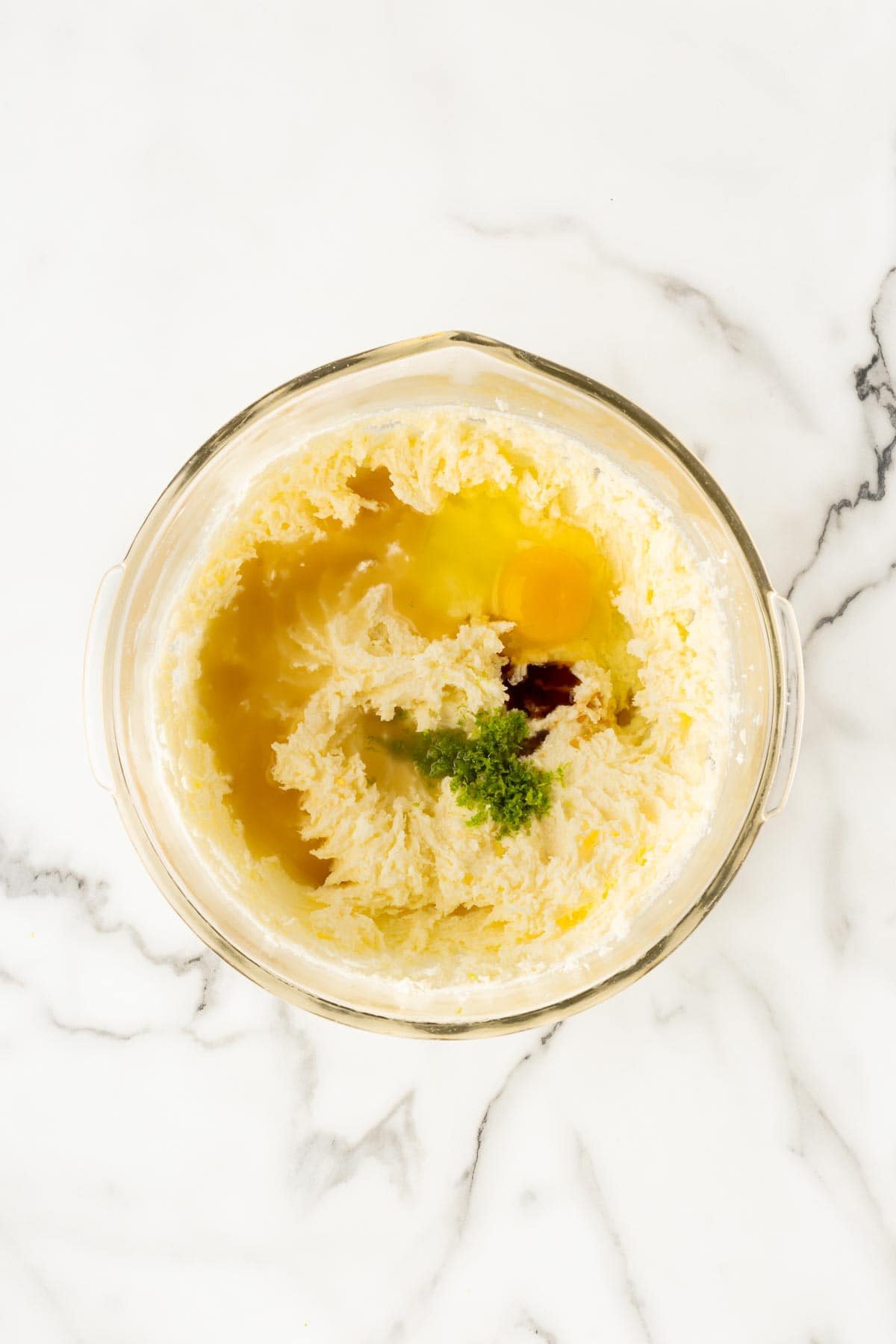 Mixing bowl with butter, sugar mixture, eggs, lime zest, and vanilla