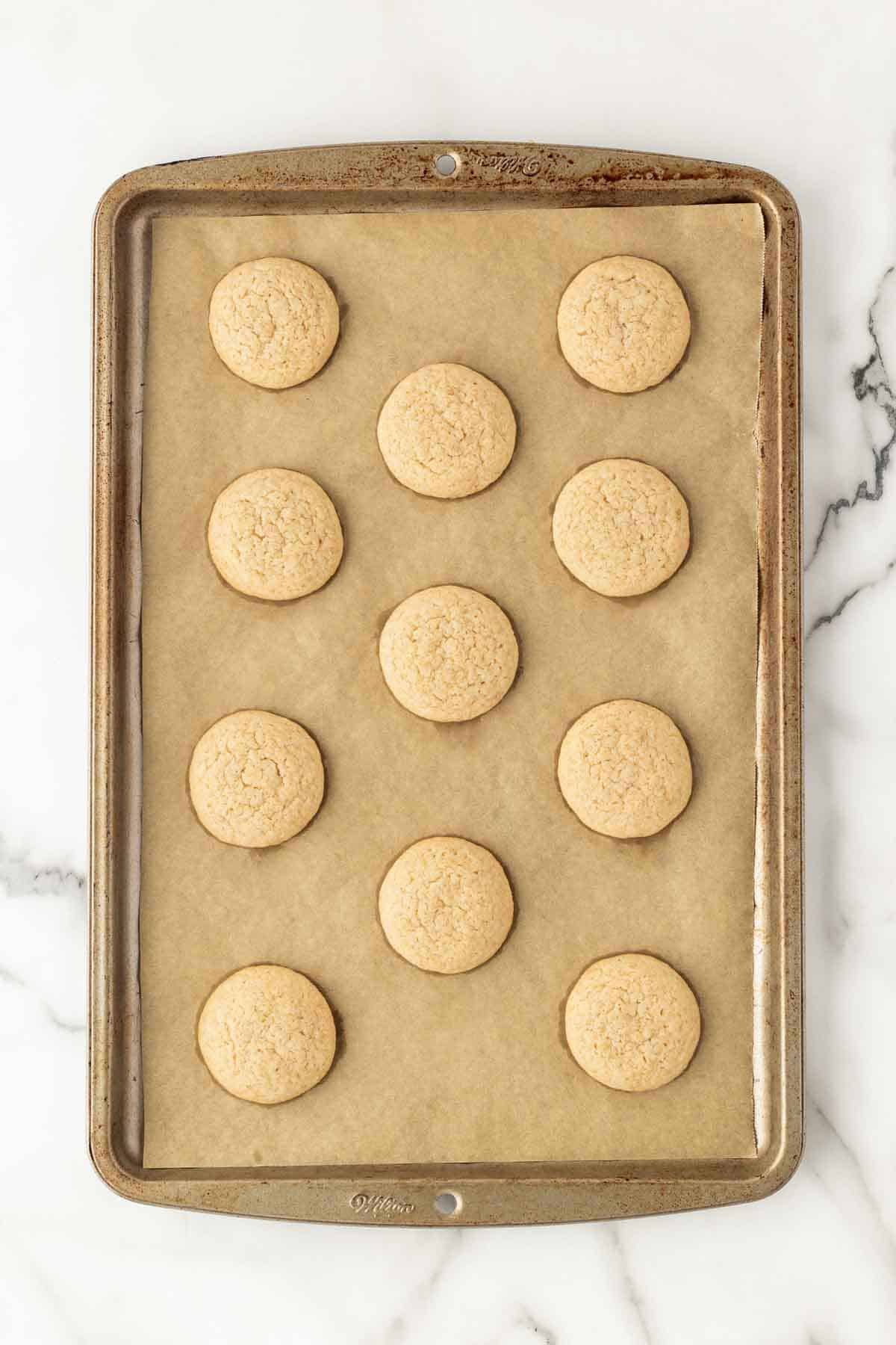 Baked key lime pie cookies cooling on parchment-lined baking sheet
