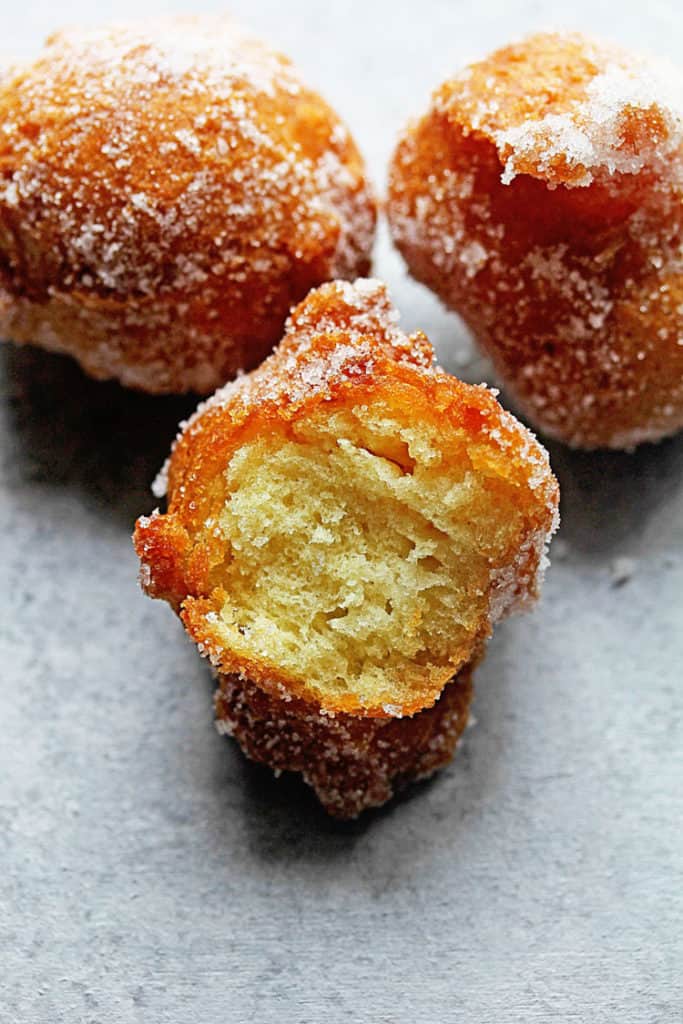 Close up of a half eaten Castagnole (Italian Fried Dough Balls with Sugar) covered in sugar