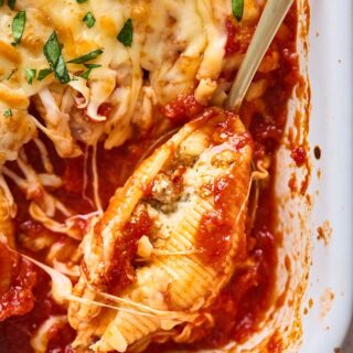 A close up of a sausage stuffed shell in tomato sauce with cheesy baked option