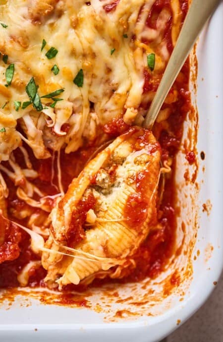 A close up of a sausage stuffed shell in tomato sauce with cheesy baked option