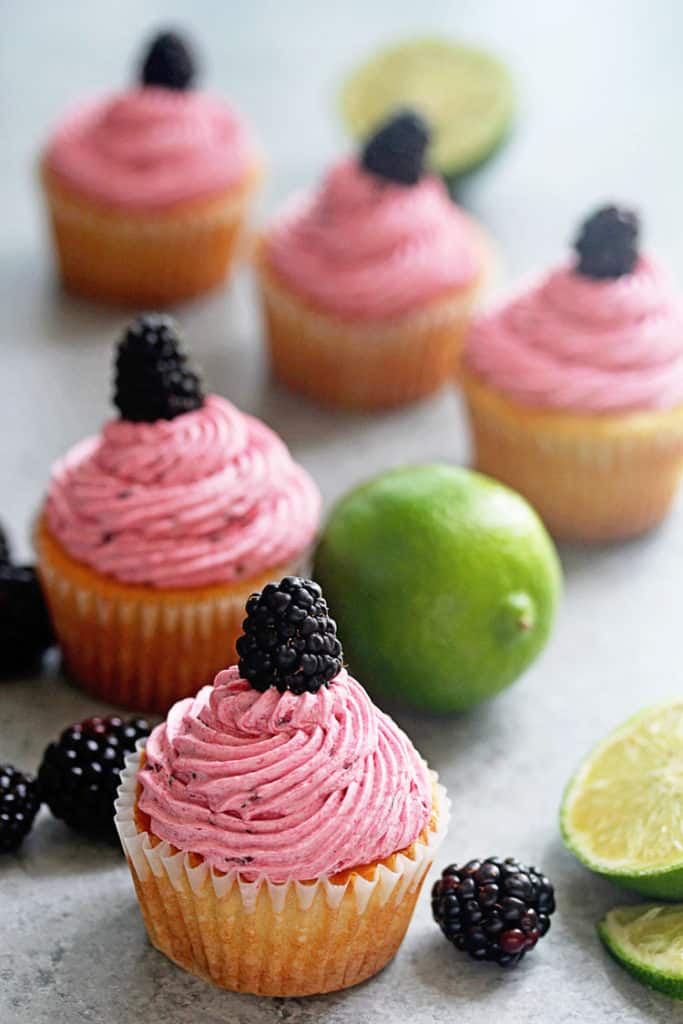 Blackberry lime cupcakes surrounded by blackberries and limes.