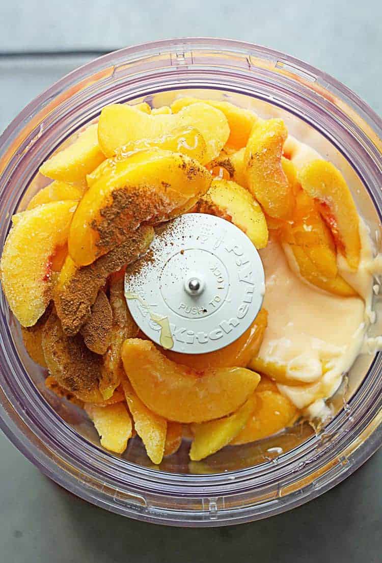 Frozen peaches, spices, sugar and yogurt in food processor ready to make a peach frozen yogurt