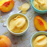 Delicious peach fro yo in small bowls with slices of peach in the background ready to serve