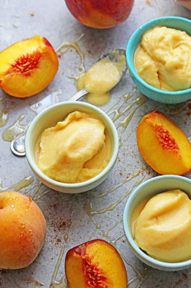 Delicious peach fro yo in small bowls with slices of peach in the background ready to serve