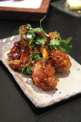 Yummy spicy chicken wings served a square, white plate at Spago in Las Vegas