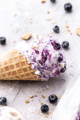 Close up of scoop of Blueberry Cheesecake Ice Cream in Waffle Cone