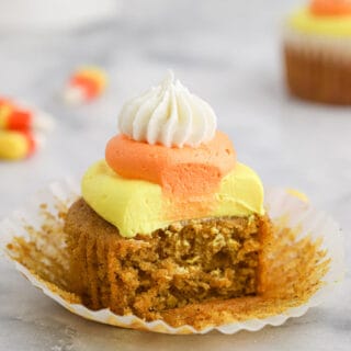 A pumpkin cupcake with paper peeled back and a bite taken to show inside of cupcake.