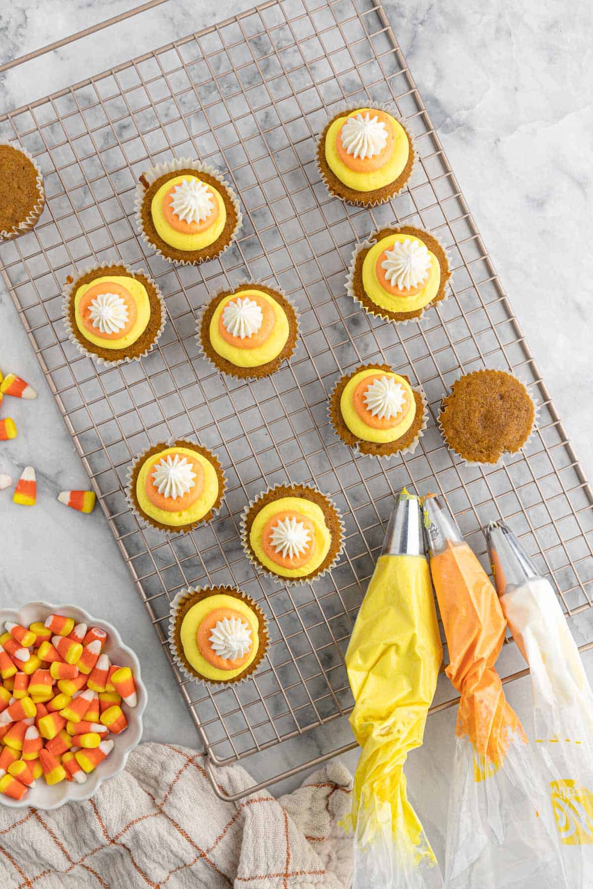 Decorated pumpkin cupcakes on a wire rack on the table.