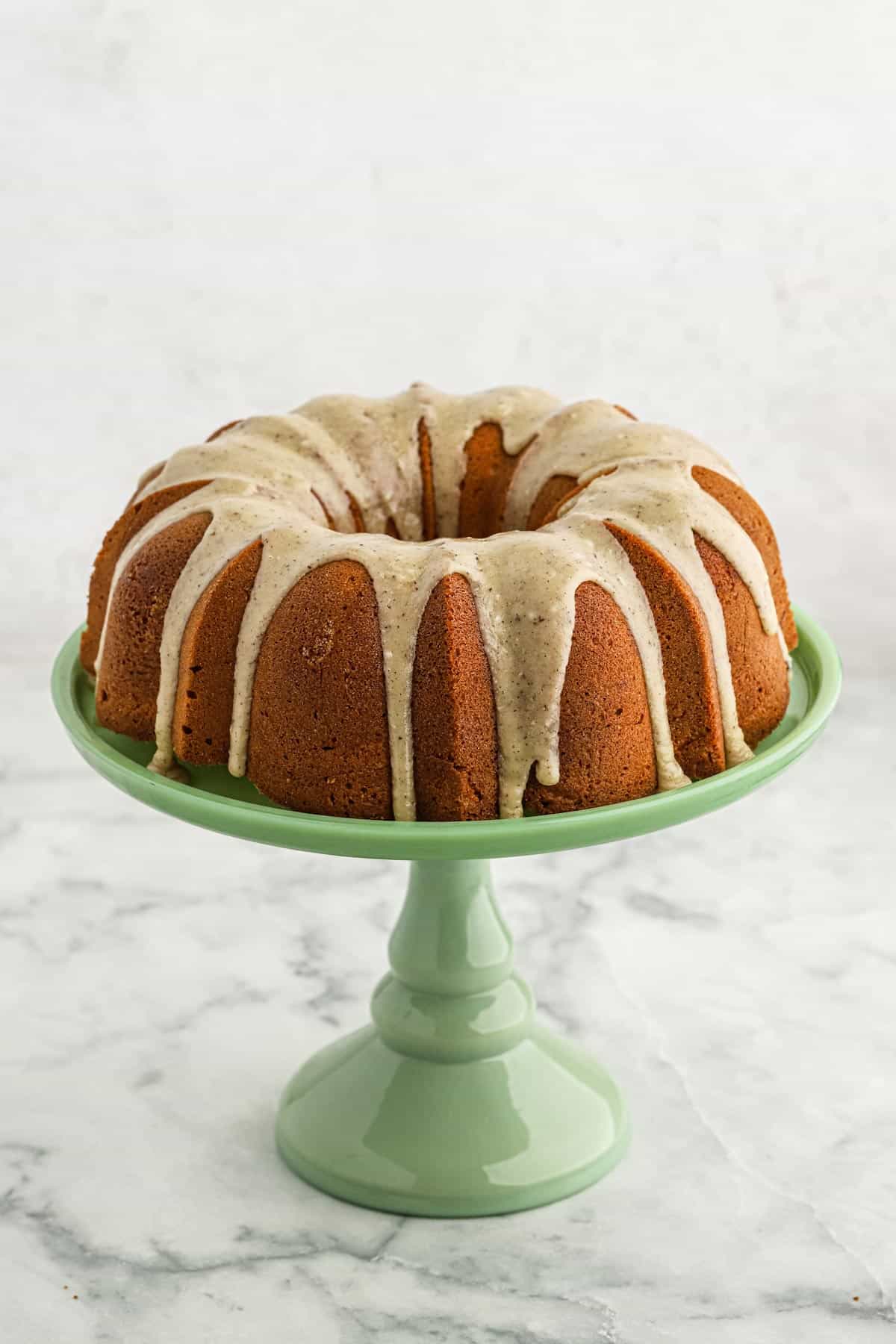 Brown sugar pound cake with glaze dripping down the sides on a green cake pedestal.