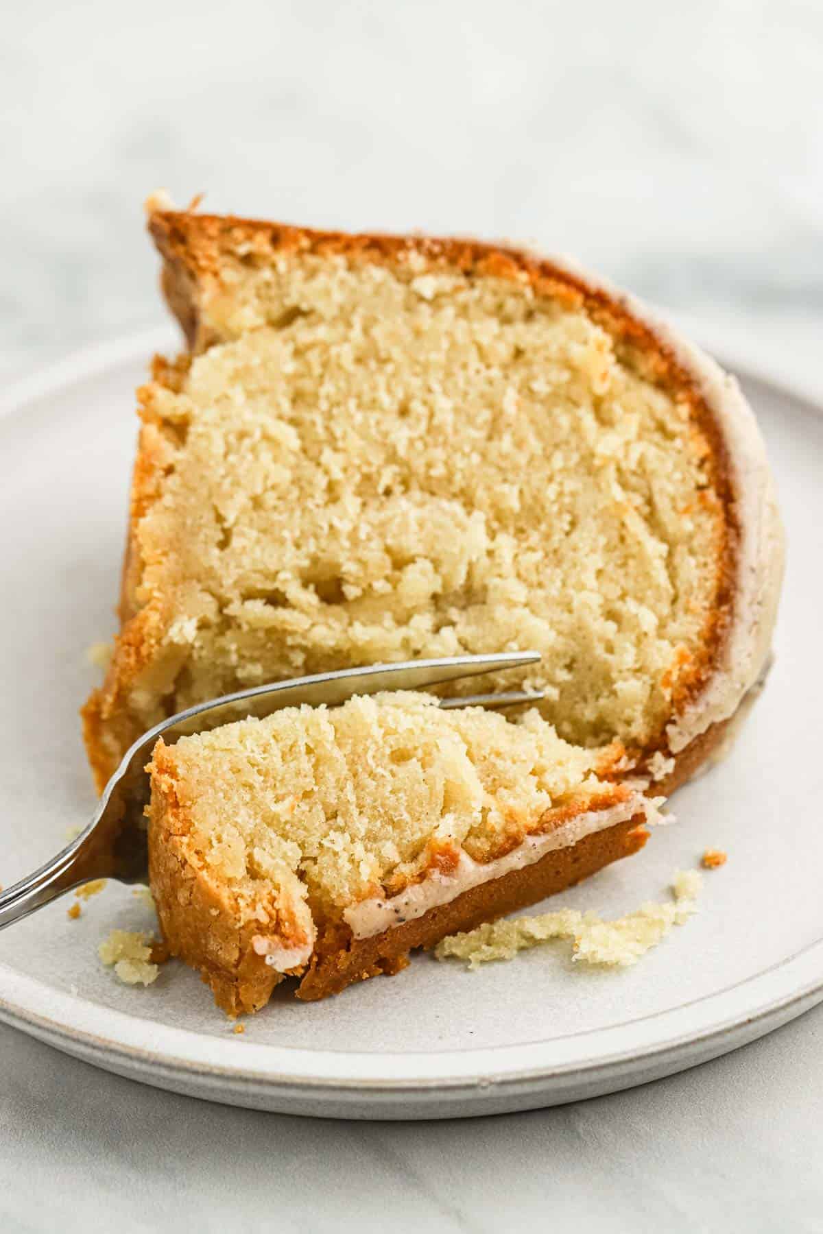 A slice of brown sugar pound cake on a plate with a fork slicing a bite.